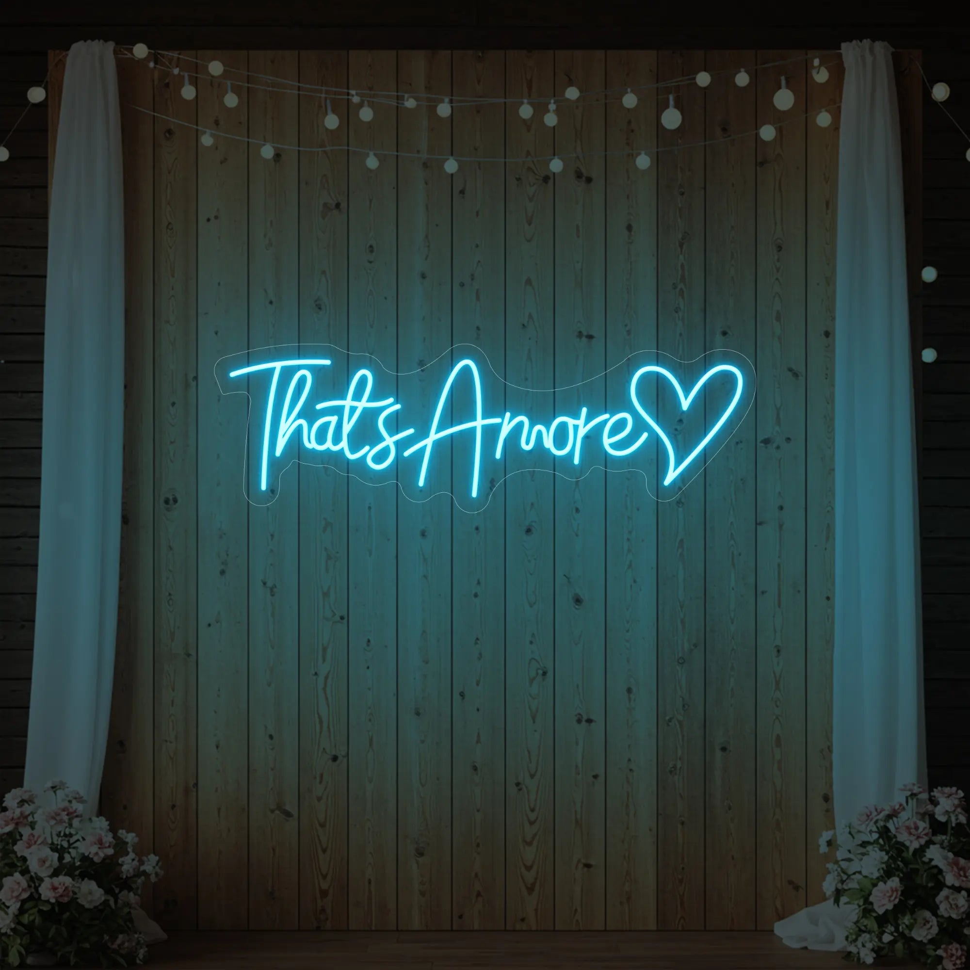 Photo of the 'That's Amore with Heart' neon sign glowing in ice blue against a styled interior wall.
