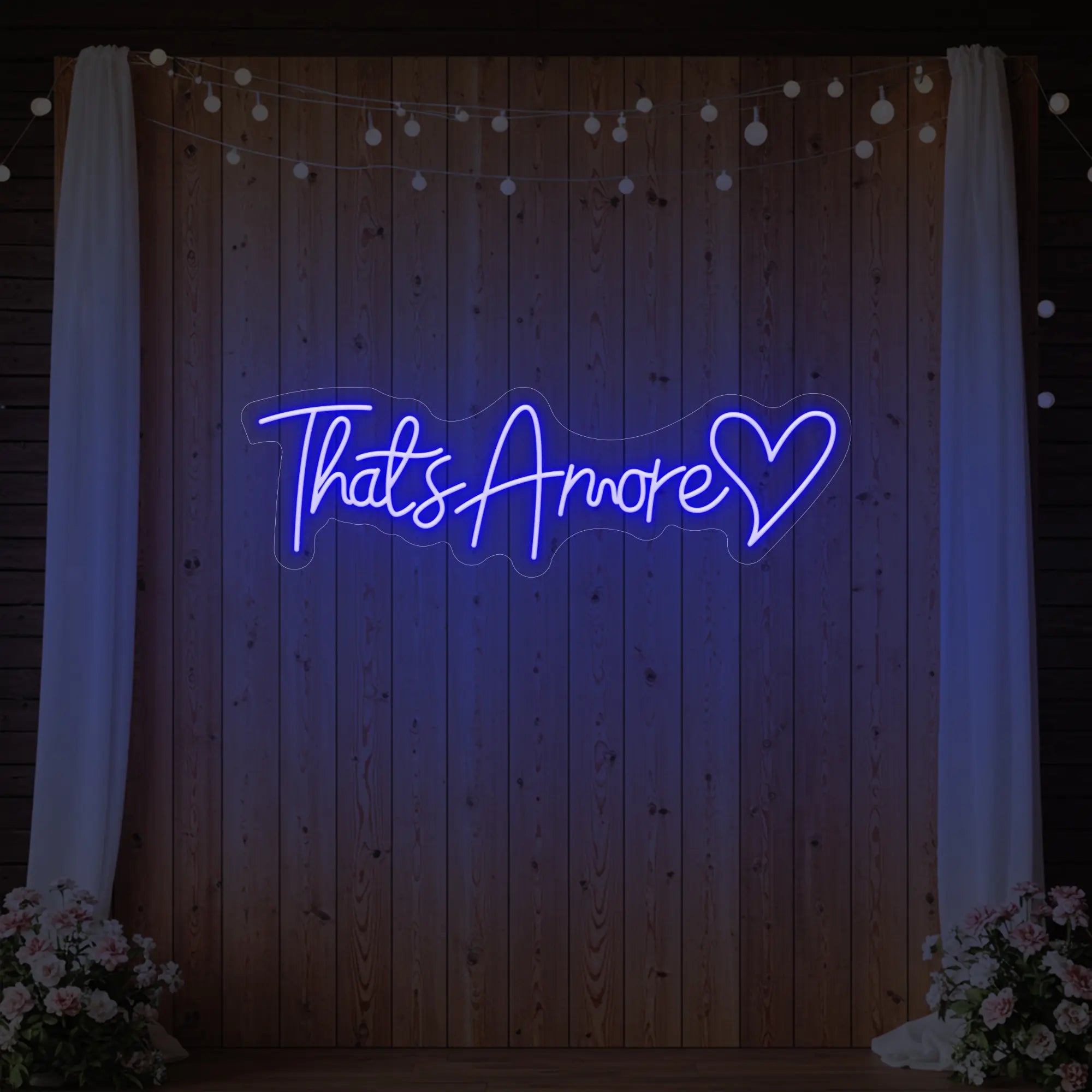 Photo of the 'That's Amore with Heart' neon sign glowing in deep blue against a styled interior wall.