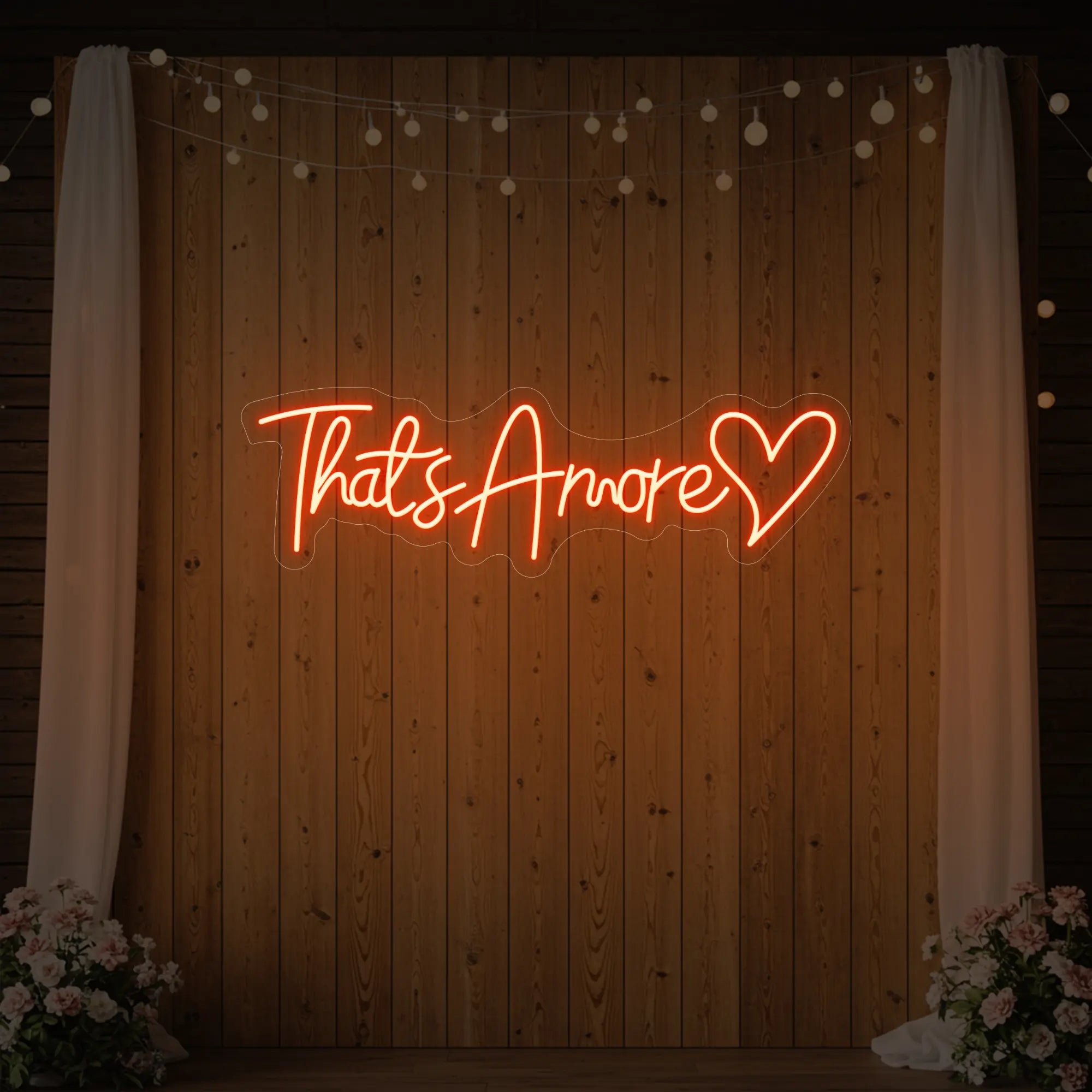 Photo of the 'That's Amore with Heart' neon sign glowing in golden yellow against a styled interior wall.