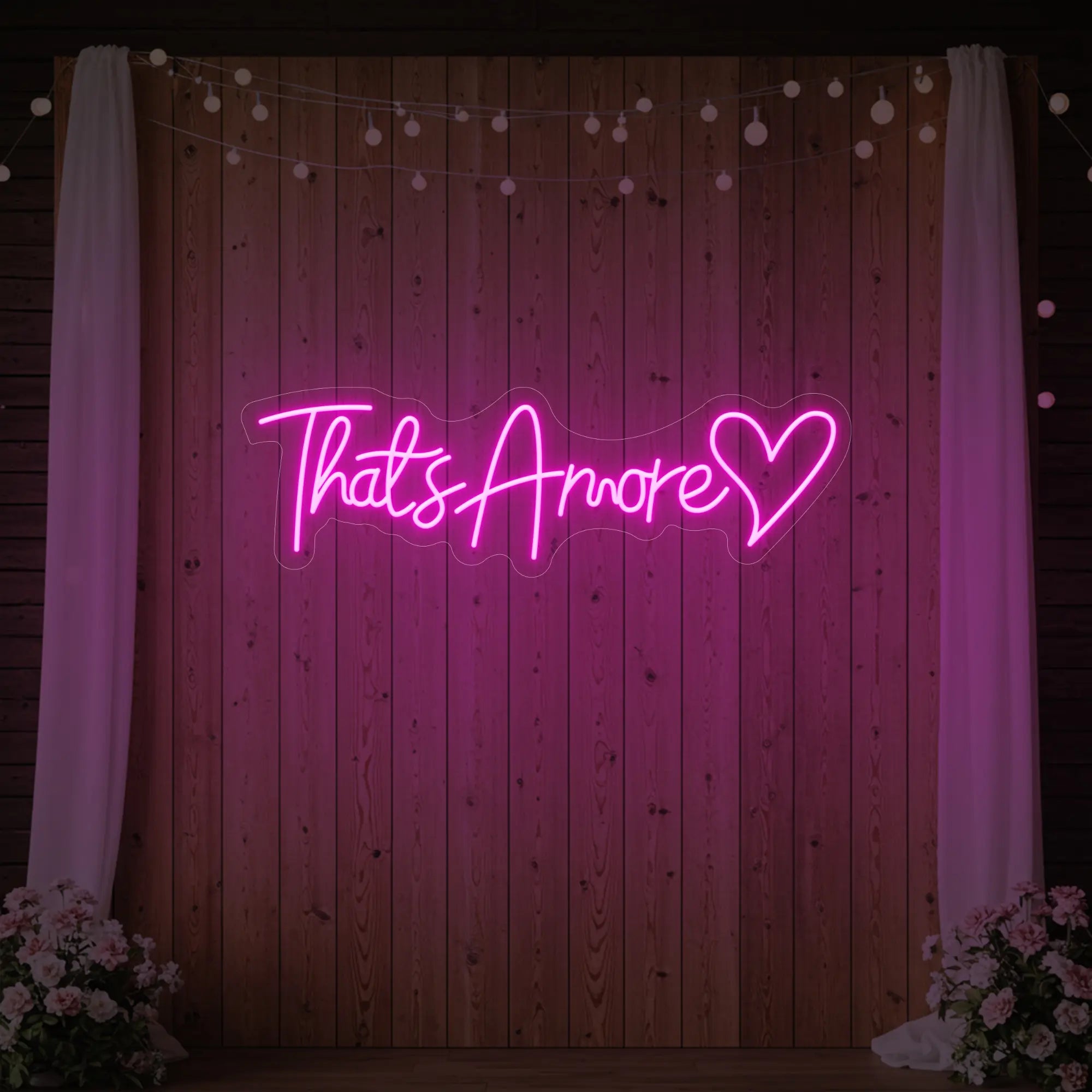 Photo of the 'That's Amore with Heart' neon sign glowing in light pink against a styled interior wall.