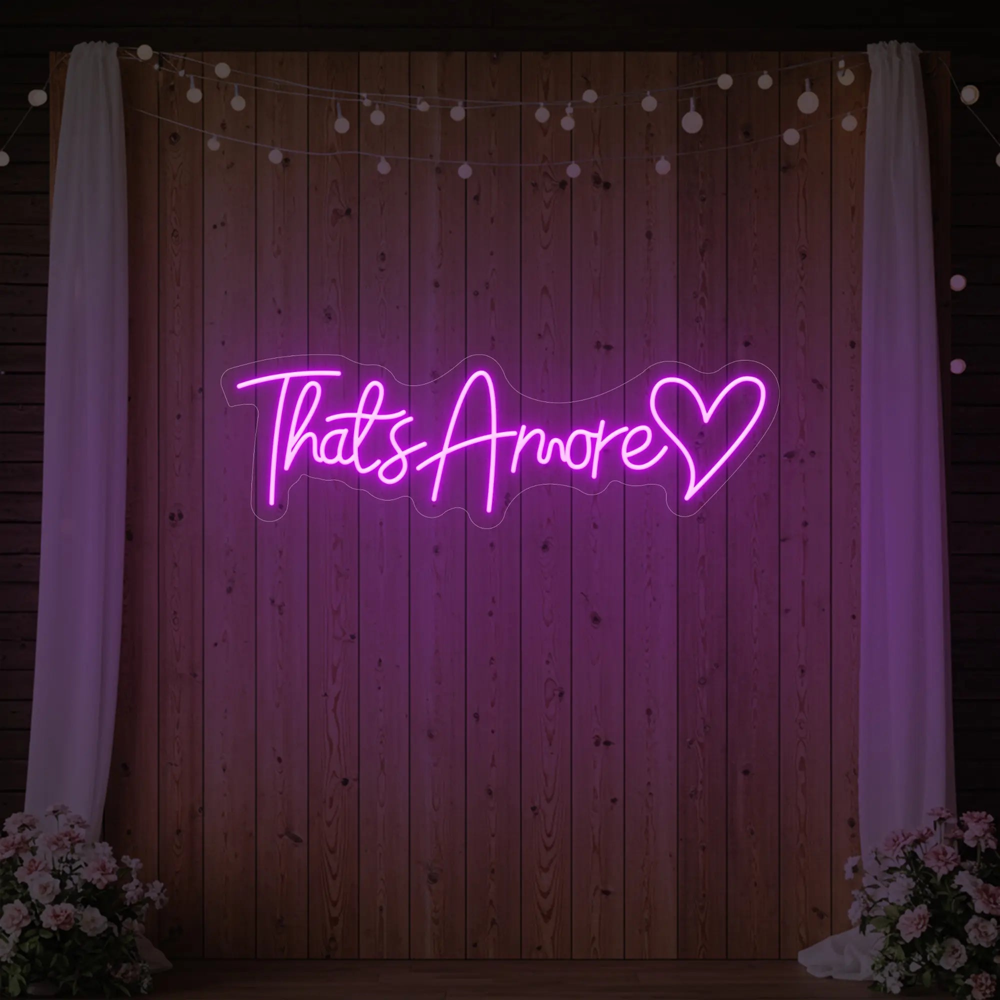 Photo of the 'That's Amore with Heart' neon sign glowing in deep pink against a styled interior wall.