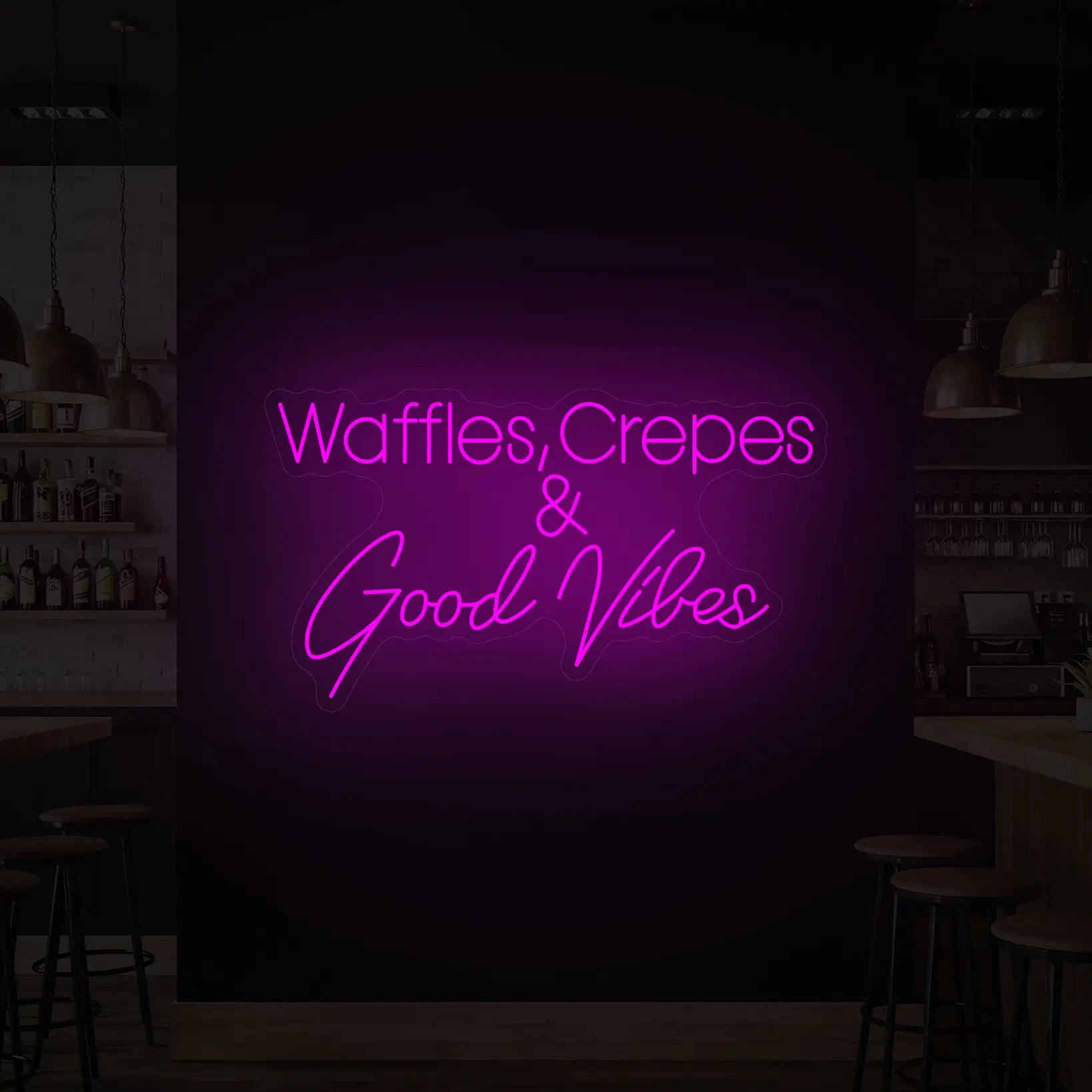 Photo of the 'WAFFLES, CREPES & GOOD VIBES' neon sign glowing in deep pink against a styled interior wall.