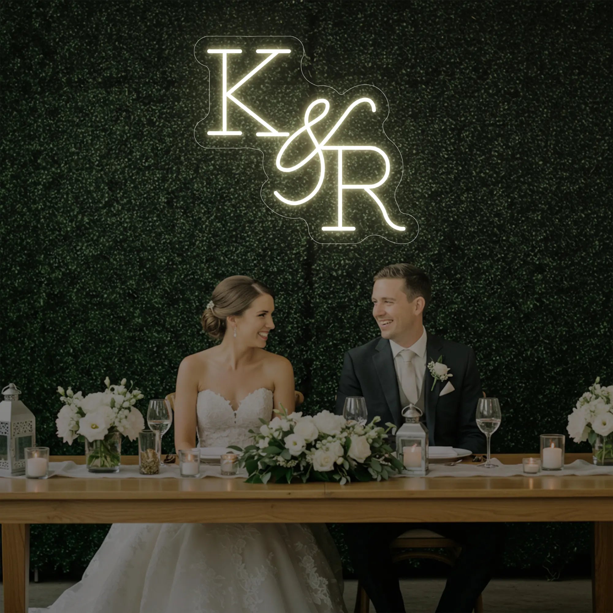 Photo of the 'Wedding Initials Custom Neon Sign V2' neon sign glowing in warm white against a styled interior wall.