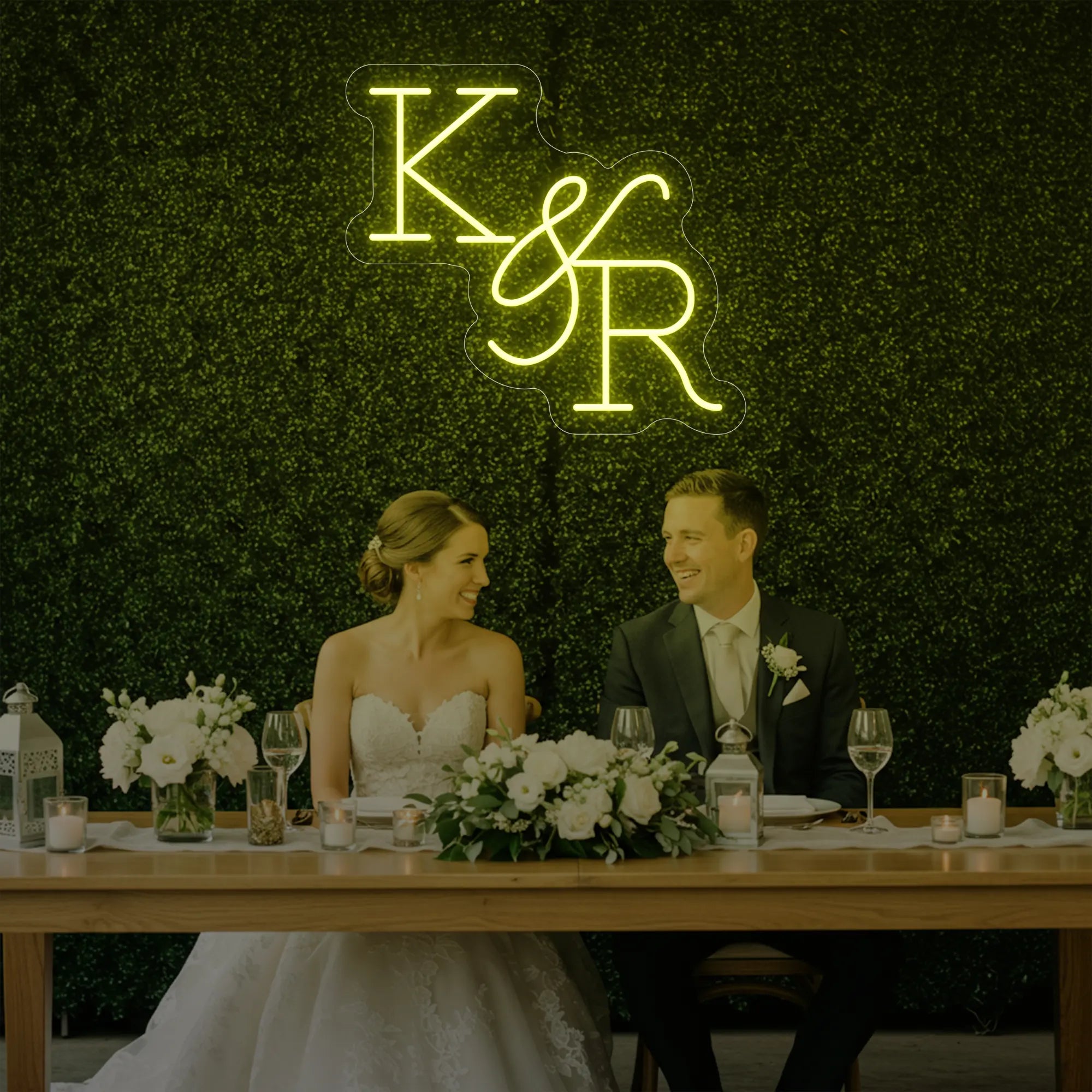 Photo of the 'Wedding Initials Custom Neon Sign V2' neon sign glowing in lemon yellow against a styled interior wall.