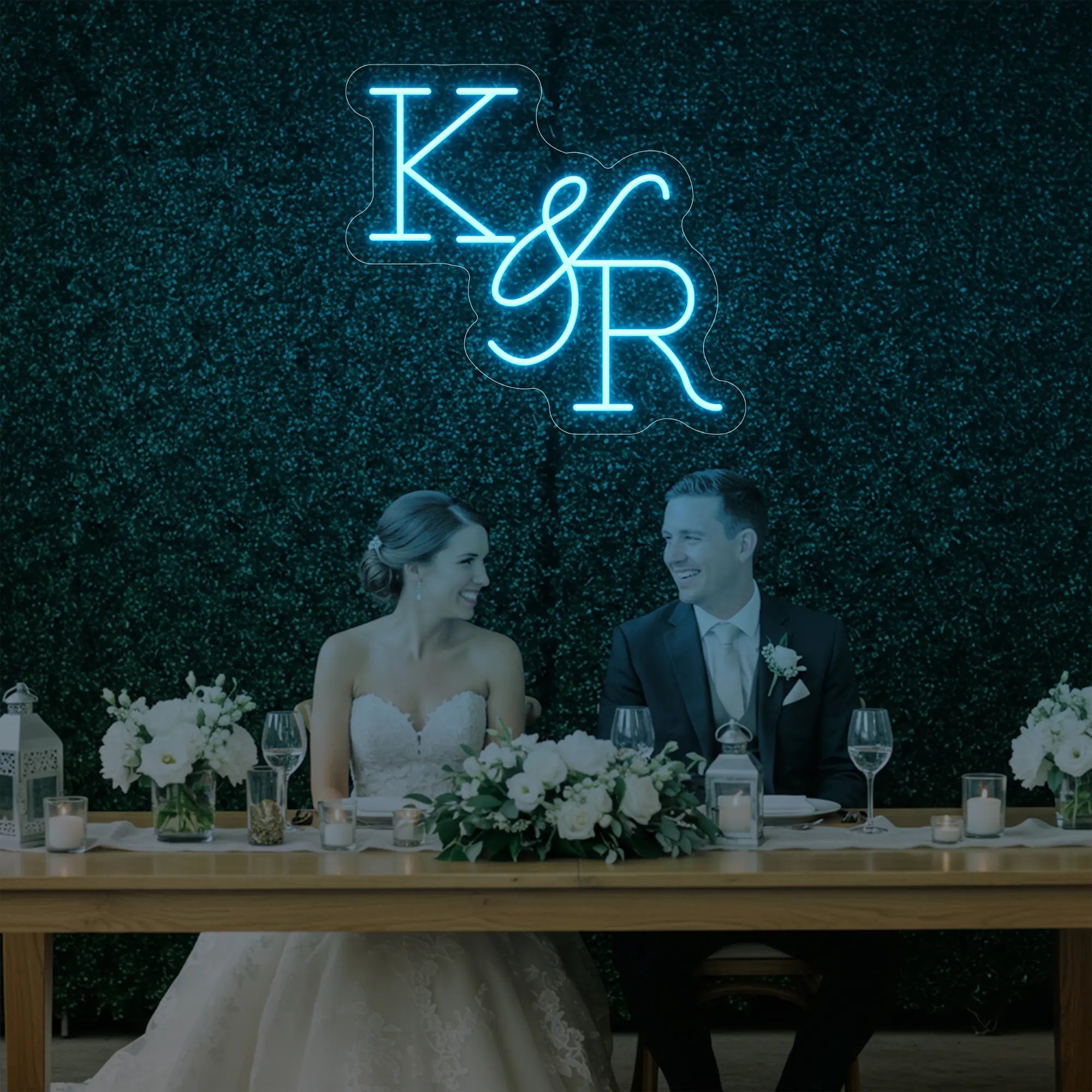Photo of the 'Wedding Initials Custom Neon Sign V2' neon sign glowing in ice blue against a styled interior wall.