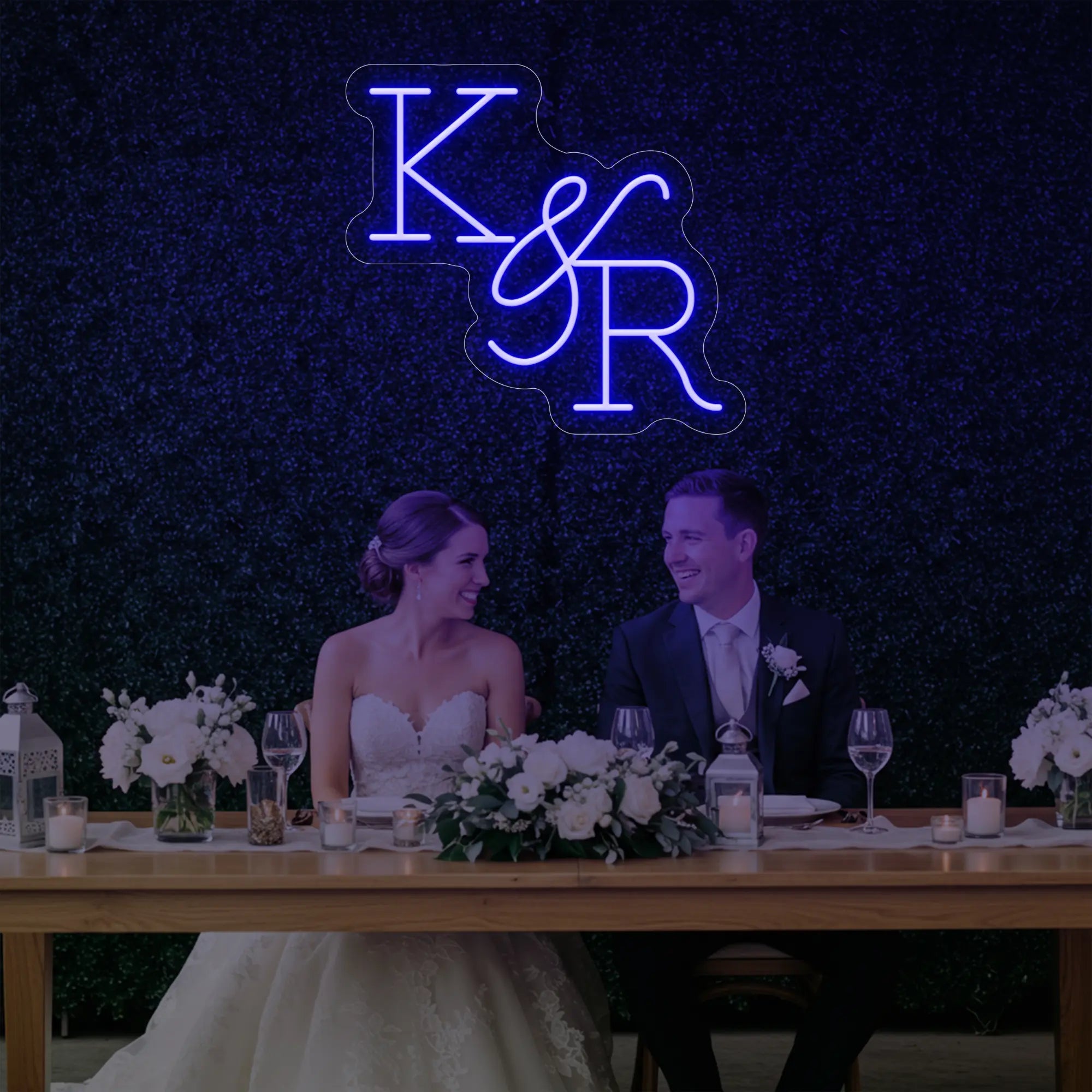 Photo of the 'Wedding Initials Custom Neon Sign V2' neon sign glowing in deep blue against a styled interior wall.
