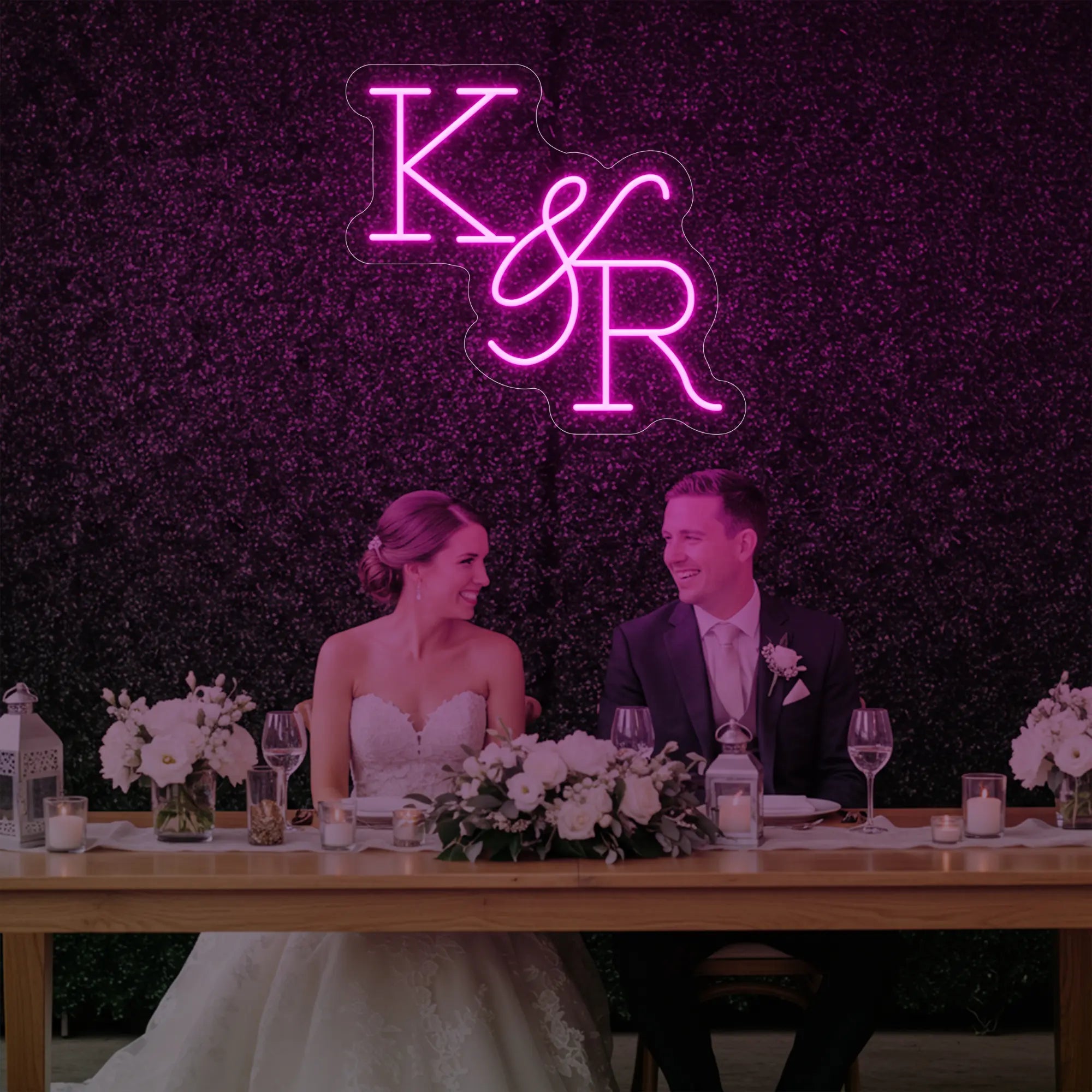 Photo of the 'Wedding Initials Custom Neon Sign V2' neon sign glowing in light pink against a styled interior wall.
