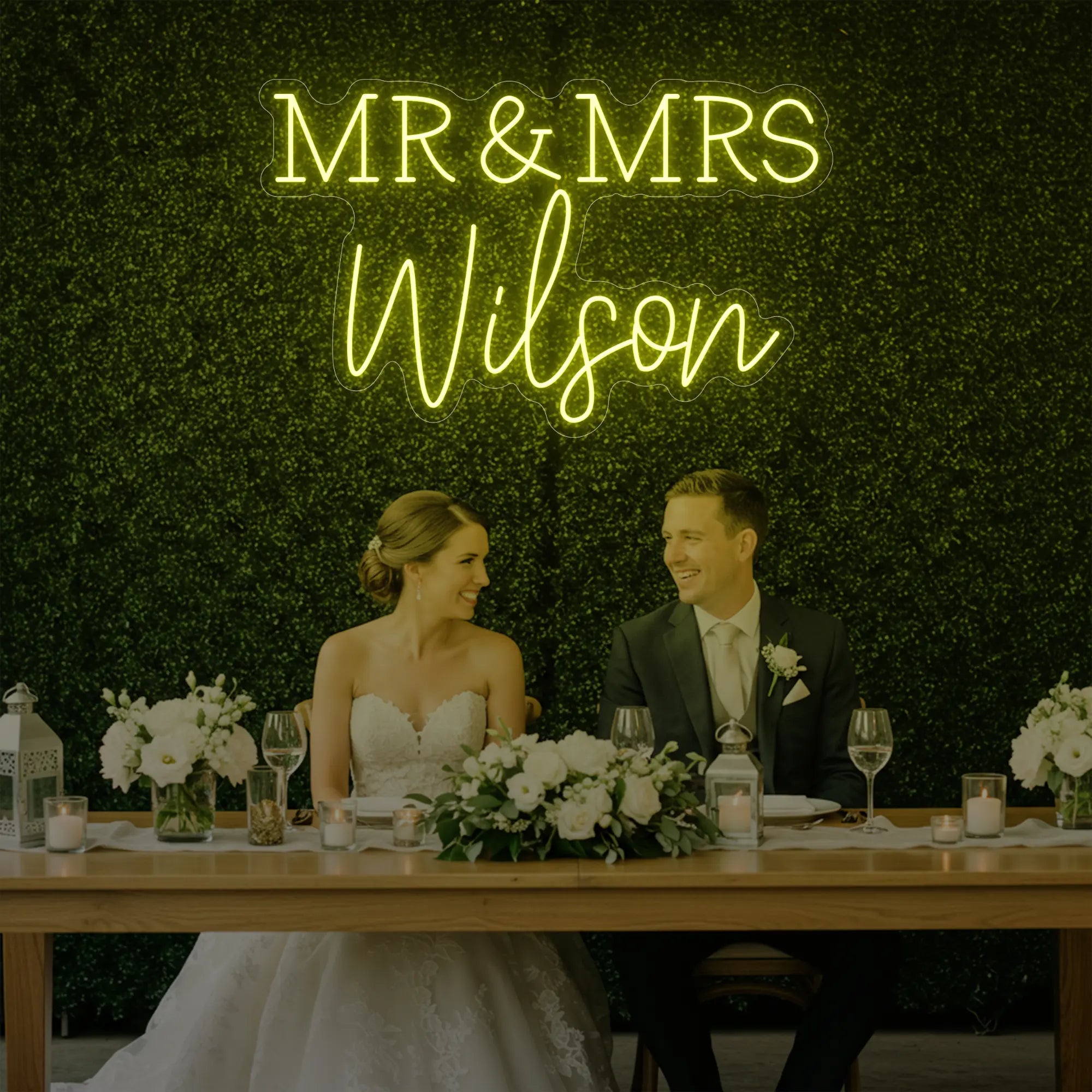 Photo of the 'Wedding Last Names Custom Neon Sign V2' neon sign glowing in lemon yellow against a styled interior wall.