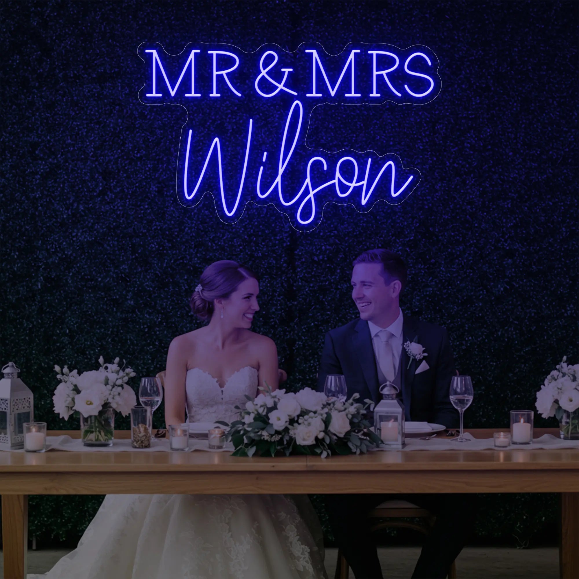 Photo of the 'Wedding Last Names Custom Neon Sign V2' neon sign glowing in deep blue against a styled interior wall.