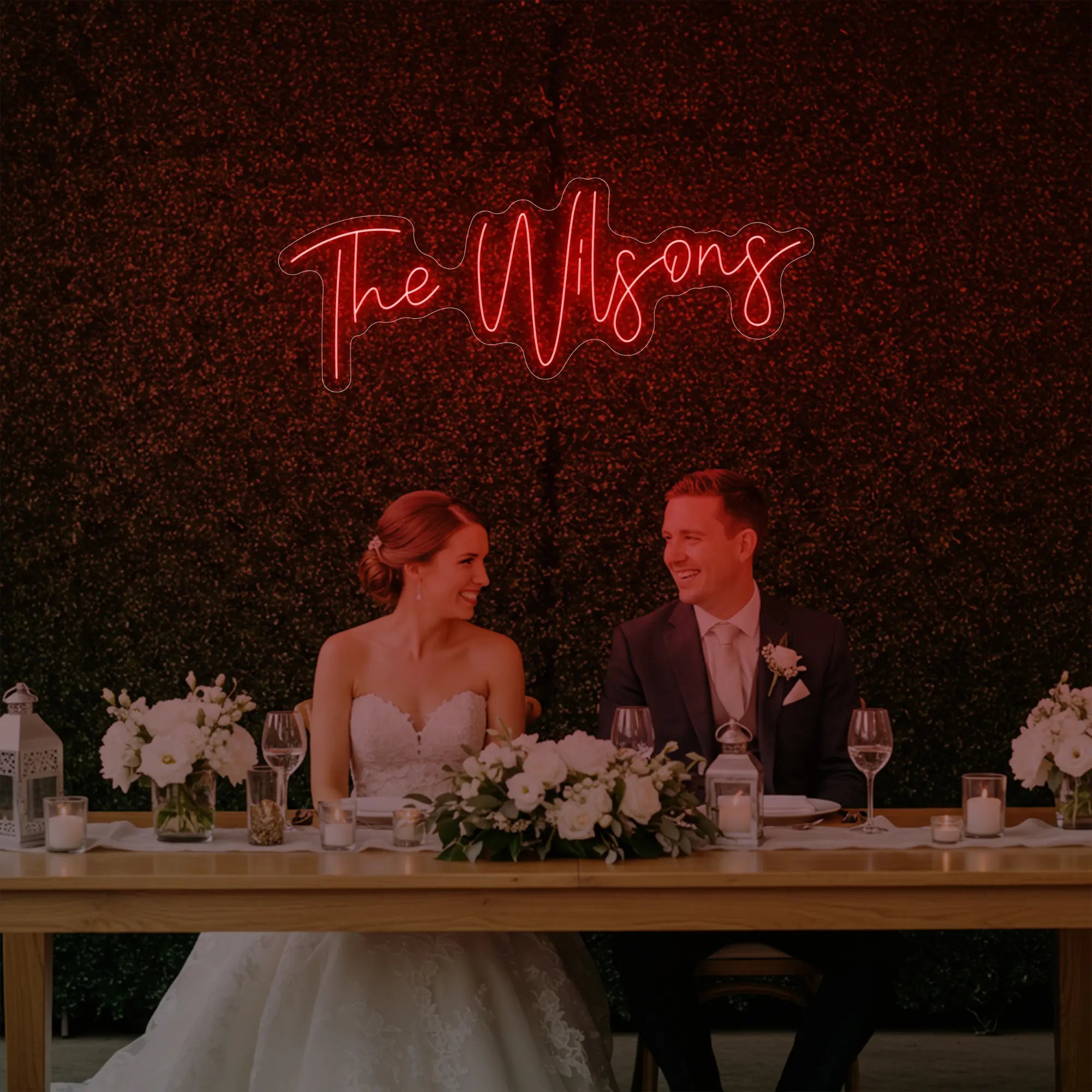 Photo of the 'Wedding Last Names Custom Neon Sign V4' neon sign glowing in red against a styled interior wall.