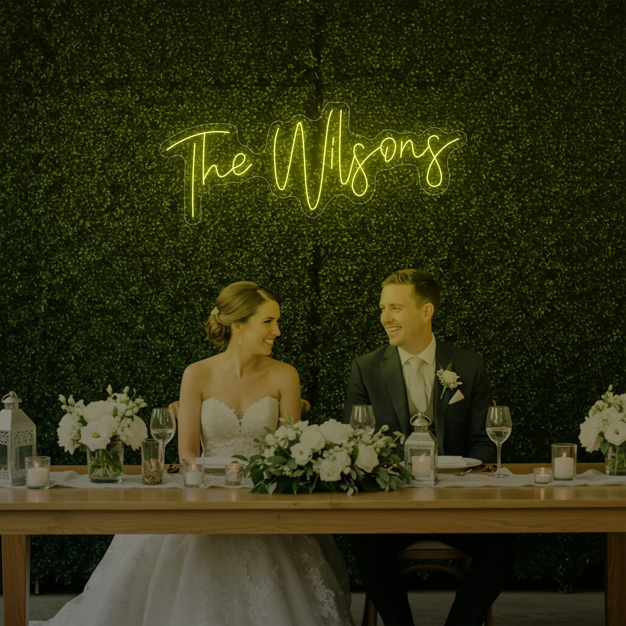 Photo of the 'Wedding Last Names Custom Neon Sign V4' neon sign glowing in lemon yellow against a styled interior wall.