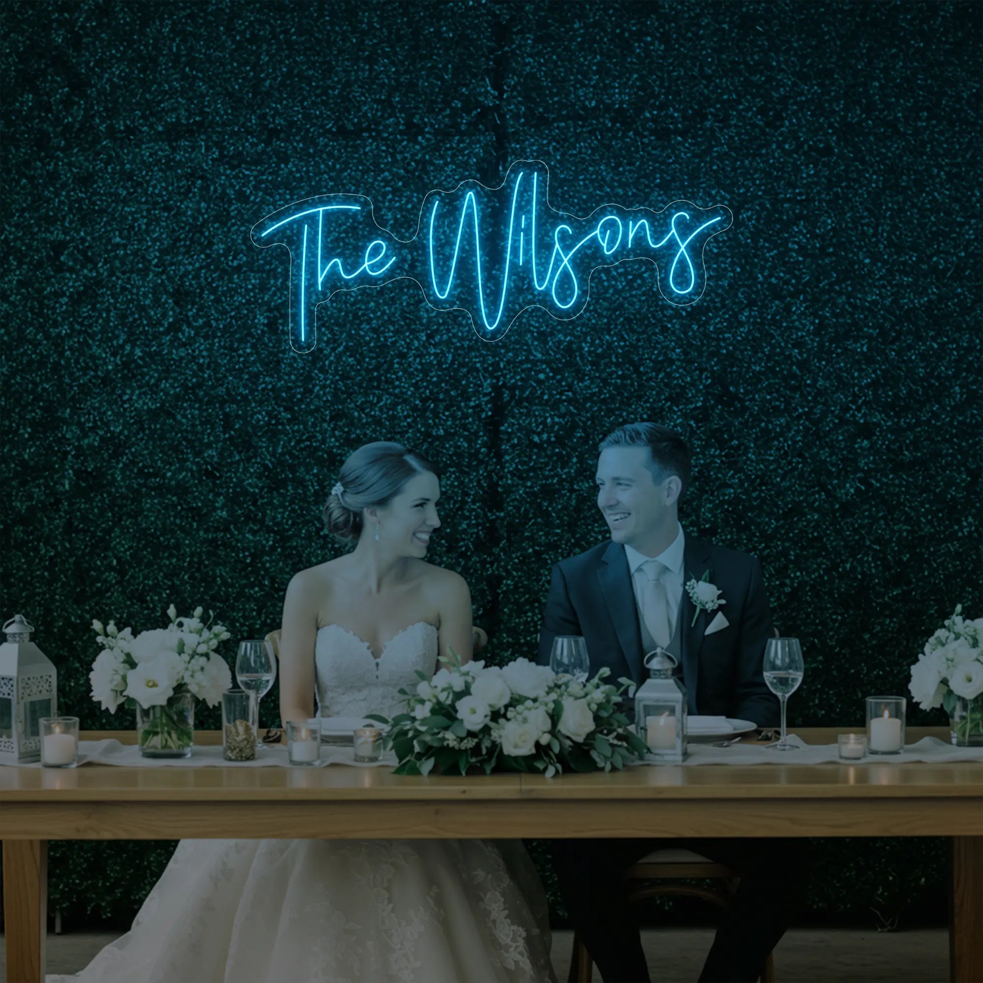 Photo of the 'Wedding Last Names Custom Neon Sign V4' neon sign glowing in ice blue against a styled interior wall.