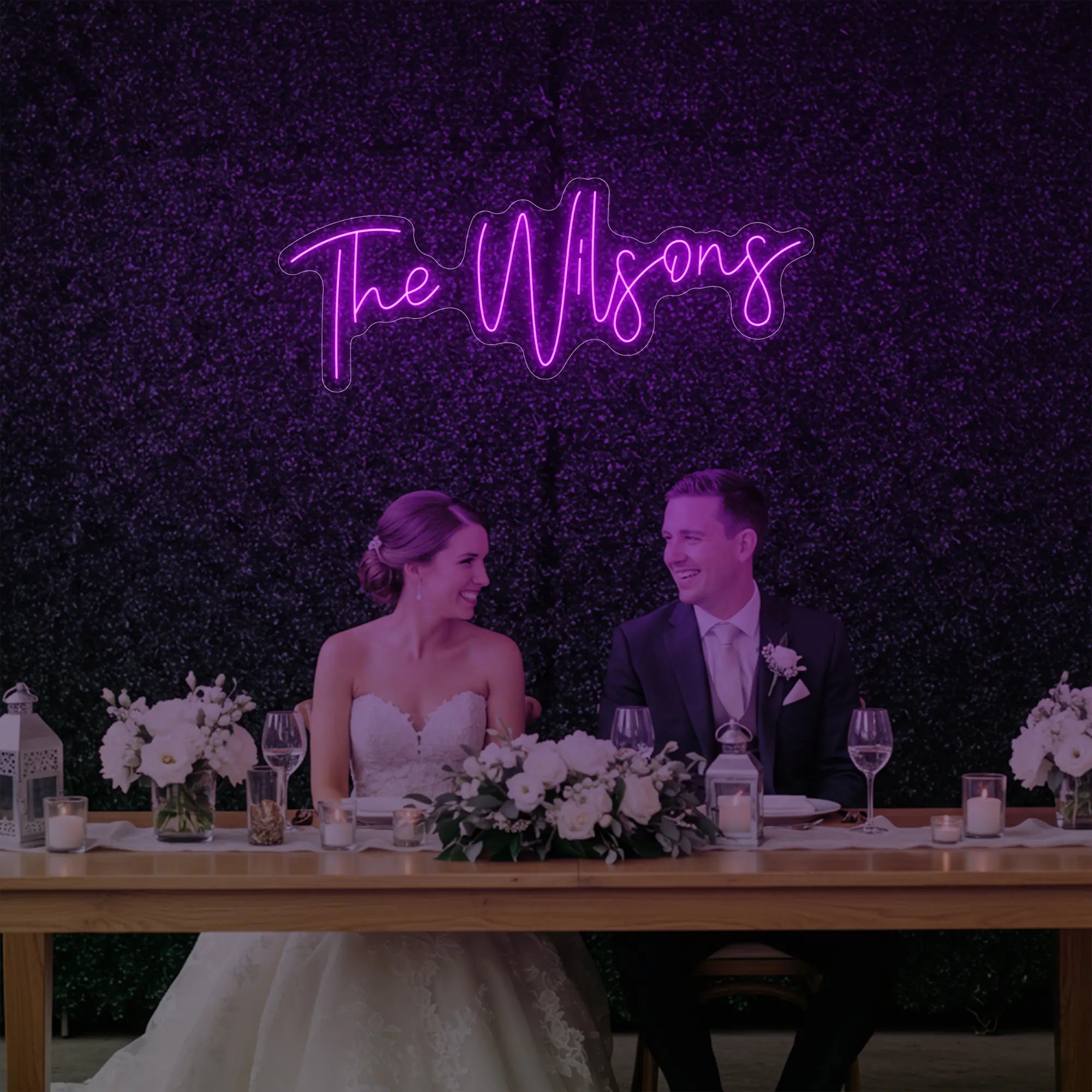 Photo of the 'Wedding Last Names Custom Neon Sign V4' neon sign glowing in deep pink against a styled interior wall.