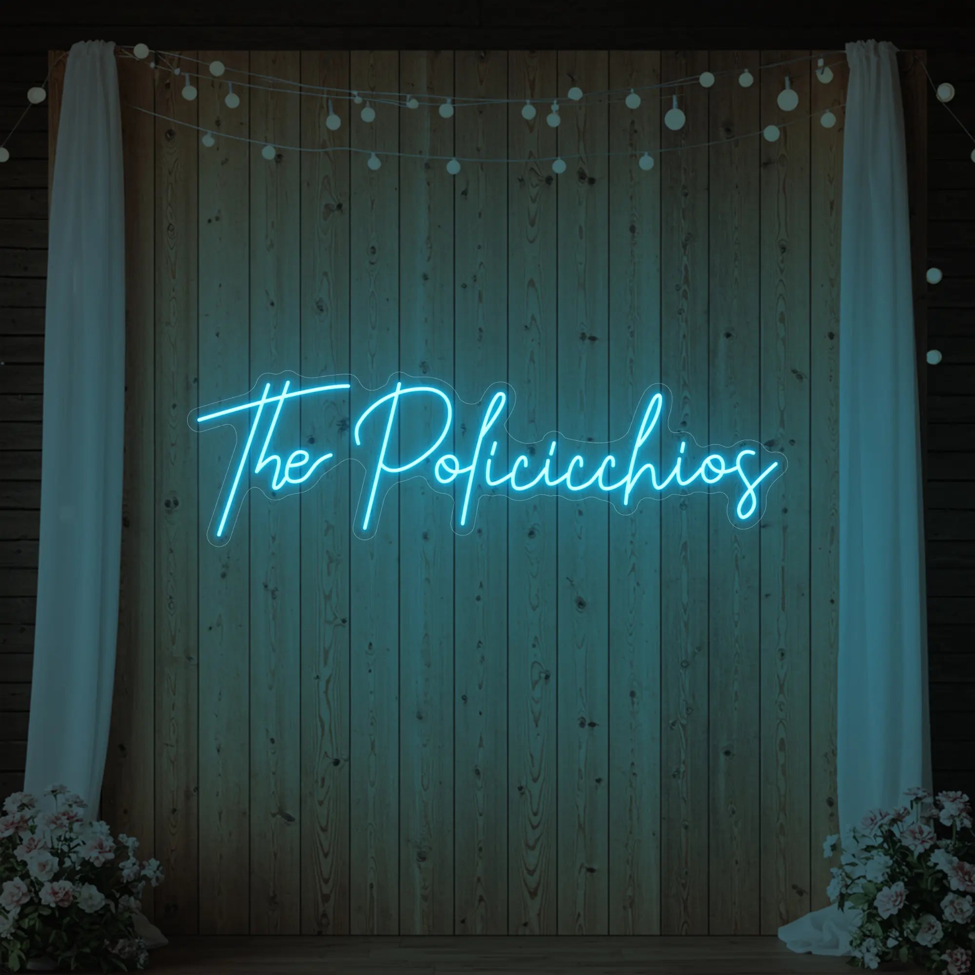Photo of the 'Wedding Last Names Custom Neon Sign V7' neon sign glowing in ice blue against a styled interior wall.