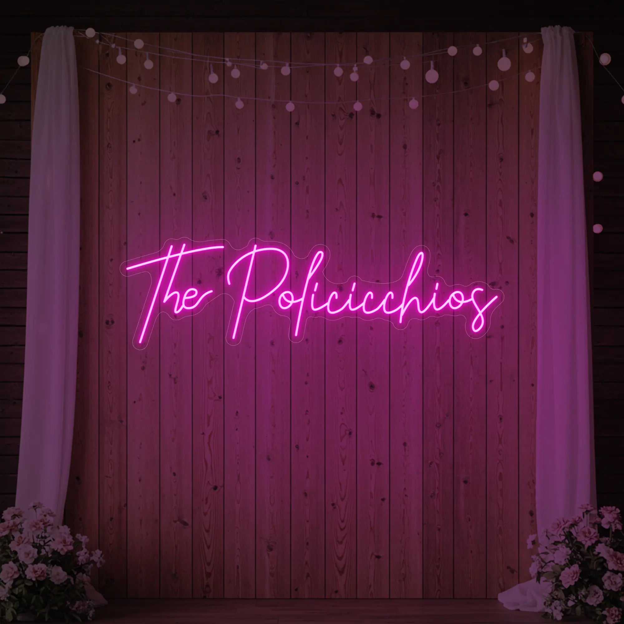 Photo of the 'Wedding Last Names Custom Neon Sign V7' neon sign glowing in light pink against a styled interior wall.