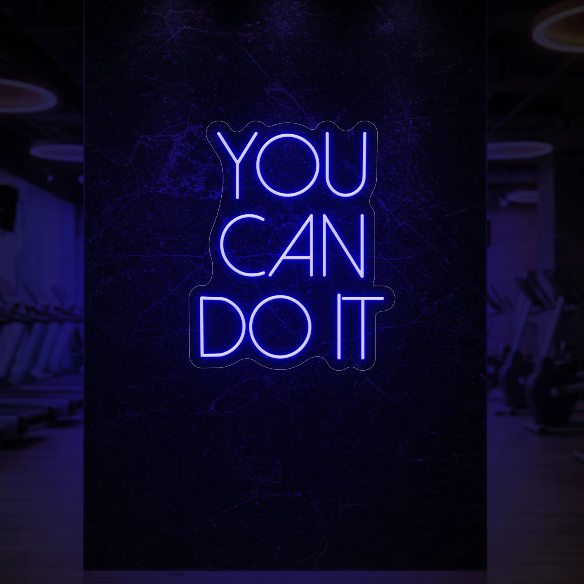 Photo of the 'YOU CAN DO IT' neon sign glowing in deep blue against a styled interior wall.