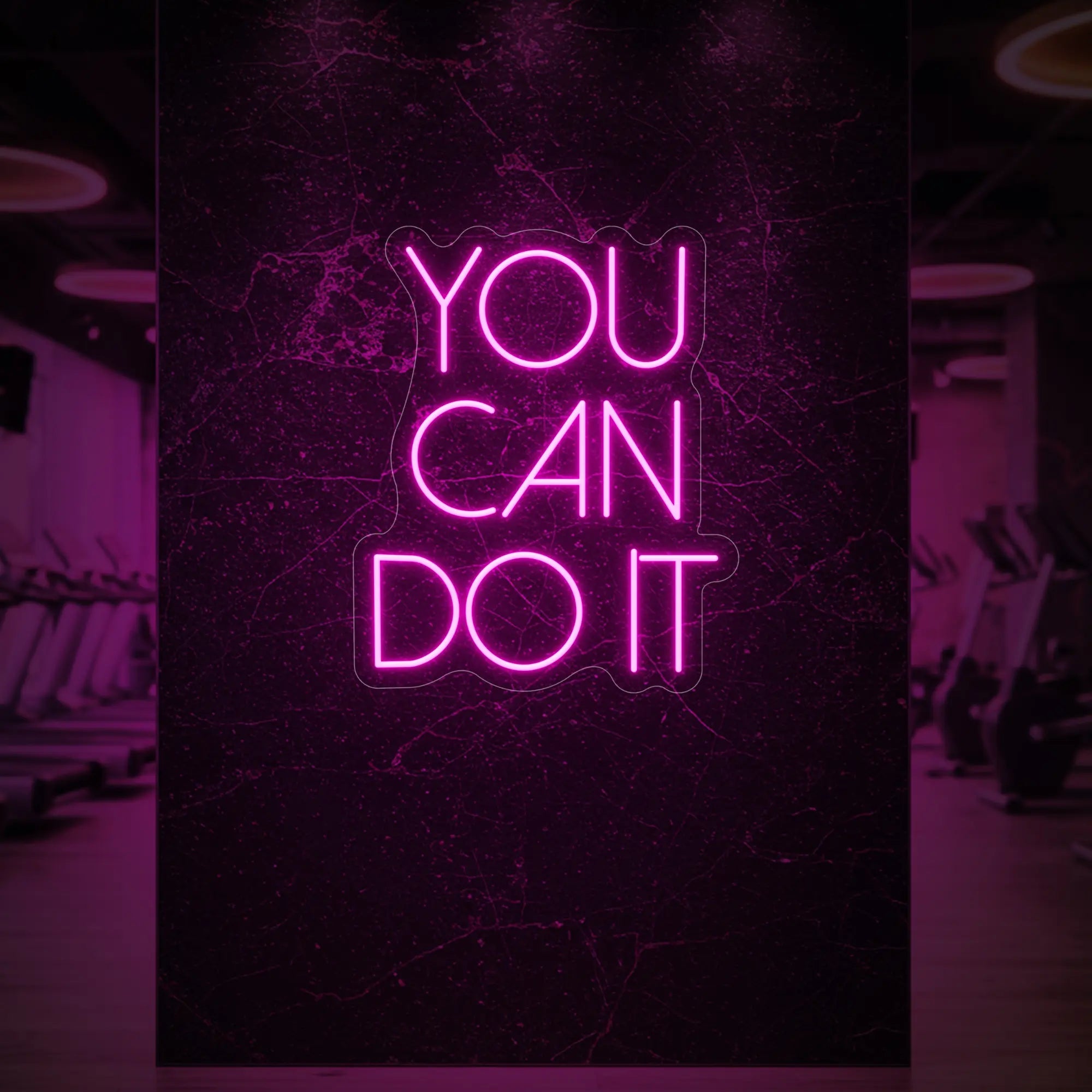 Photo of the 'YOU CAN DO IT' neon sign glowing in light pink against a styled interior wall.