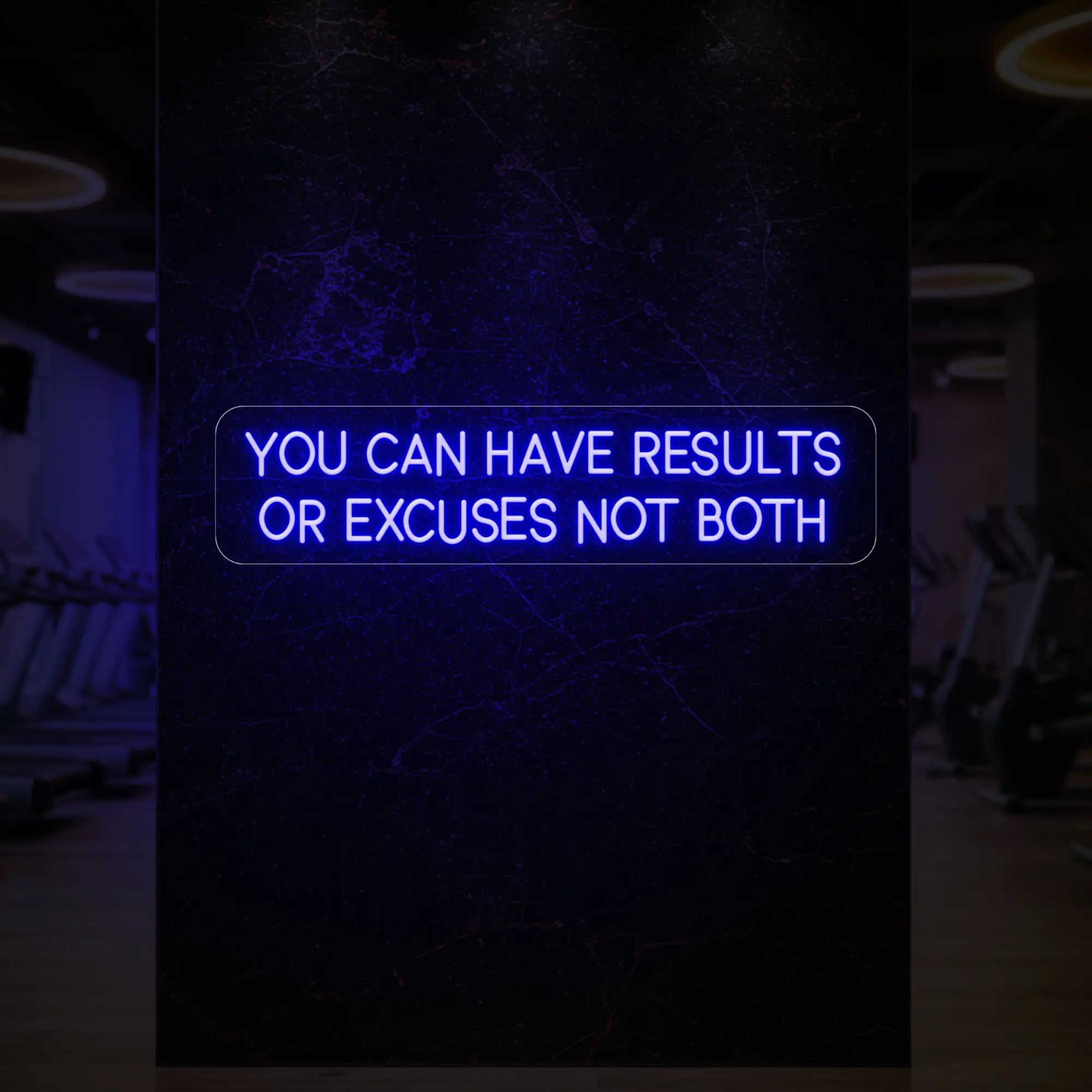 'YOU CAN HAVE RESULTS OR EXCUSES NOT BOTH' neon sign glowing in deep blue against a styled interior wall.