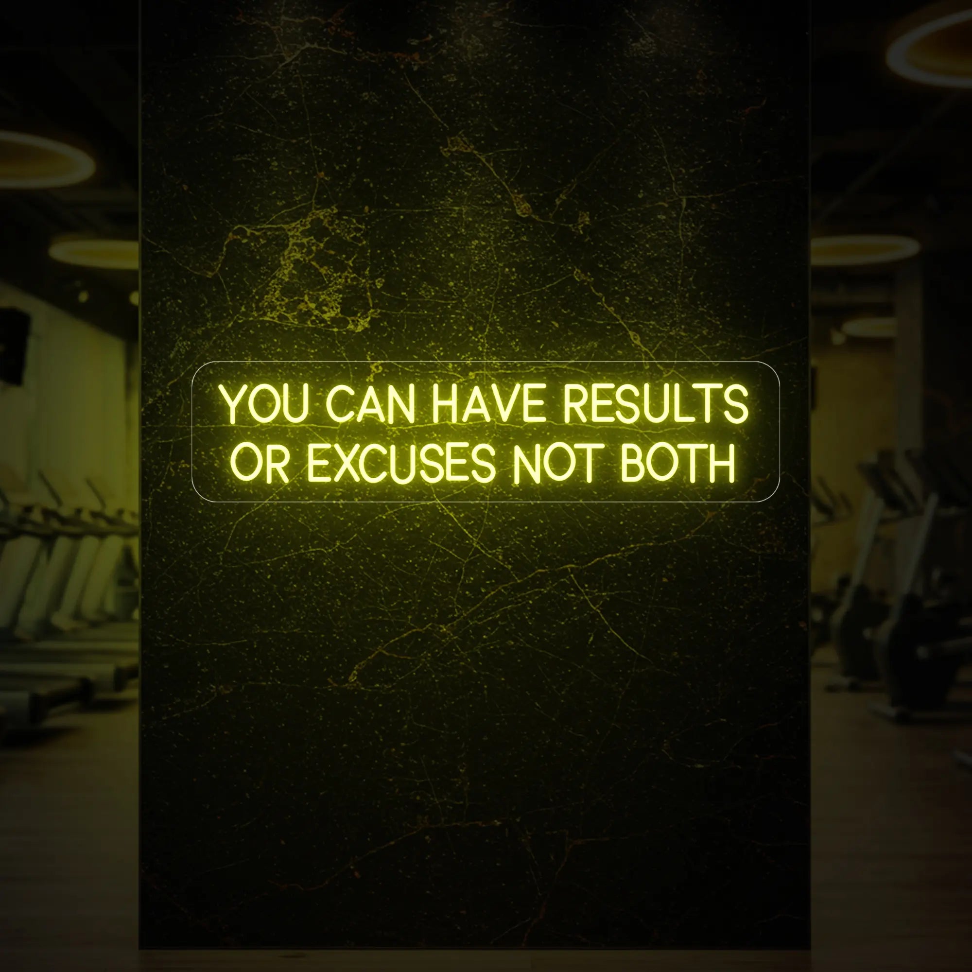 'YOU CAN HAVE RESULTS OR EXCUSES NOT BOTH' neon sign glowing in lemon yellow against a styled interior wall.
