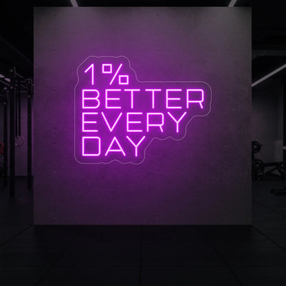  '1% Better Every Day' neon sign glowing in deep pink against a styled interior wall.