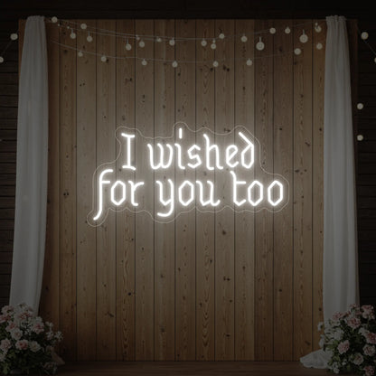 Photo of the 'I Wished For You Too' neon sign glowing in cool white against a styled interior wall.