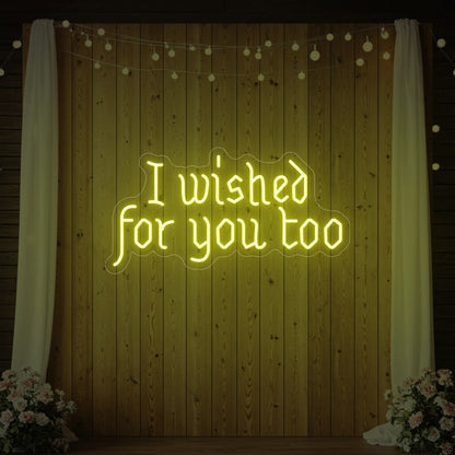 Photo of the 'I Wished For You Too' neon sign glowing in lemon yellow against a styled interior wall.
