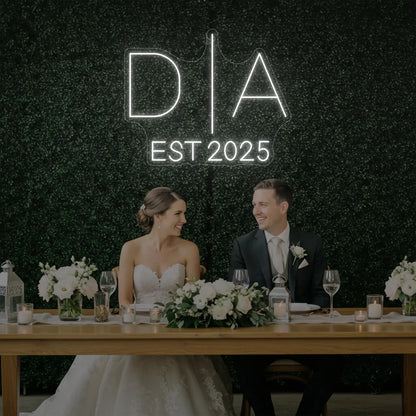 Photo of the 'Wedding Initials Custom Neon Sign V3' neon sign glowing in cool white against a styled interior wall.