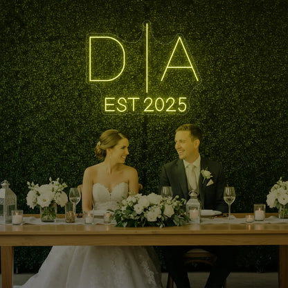 Photo of the 'Wedding Initials Custom Neon Sign V3' neon sign glowing in lemon yellow against a styled interior wall.