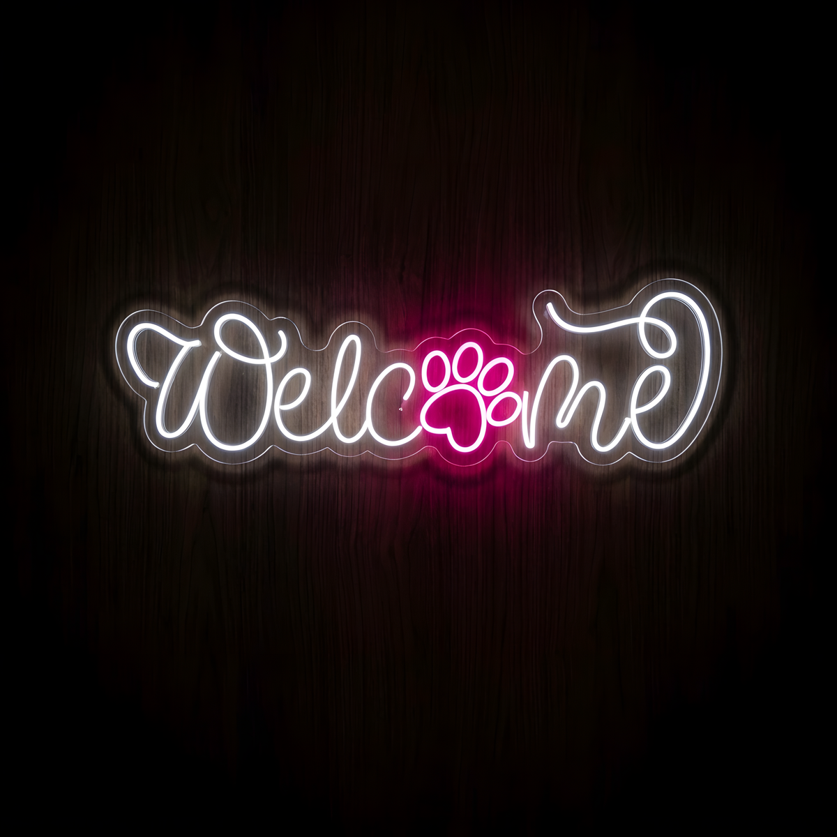 Welcome Paw LED Neon Sign with elegant glowing white script lettering and a bright pink paw print accent, displayed on clear acrylic against a dark wood wall for pet store, veterinary clinic, and grooming salon decor.
