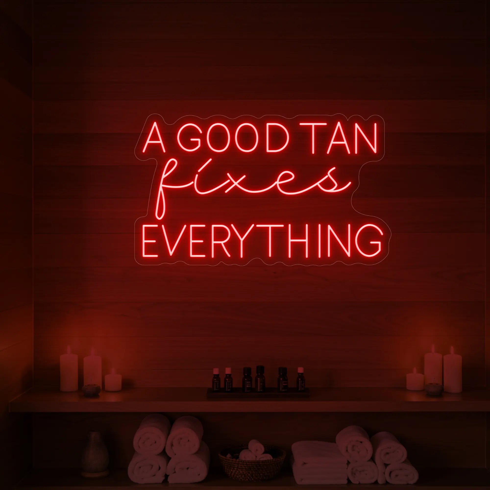 Photo of the 'A GOOD TAN fixes EVERYTHING' neon sign glowing in red against a styled interior wall.