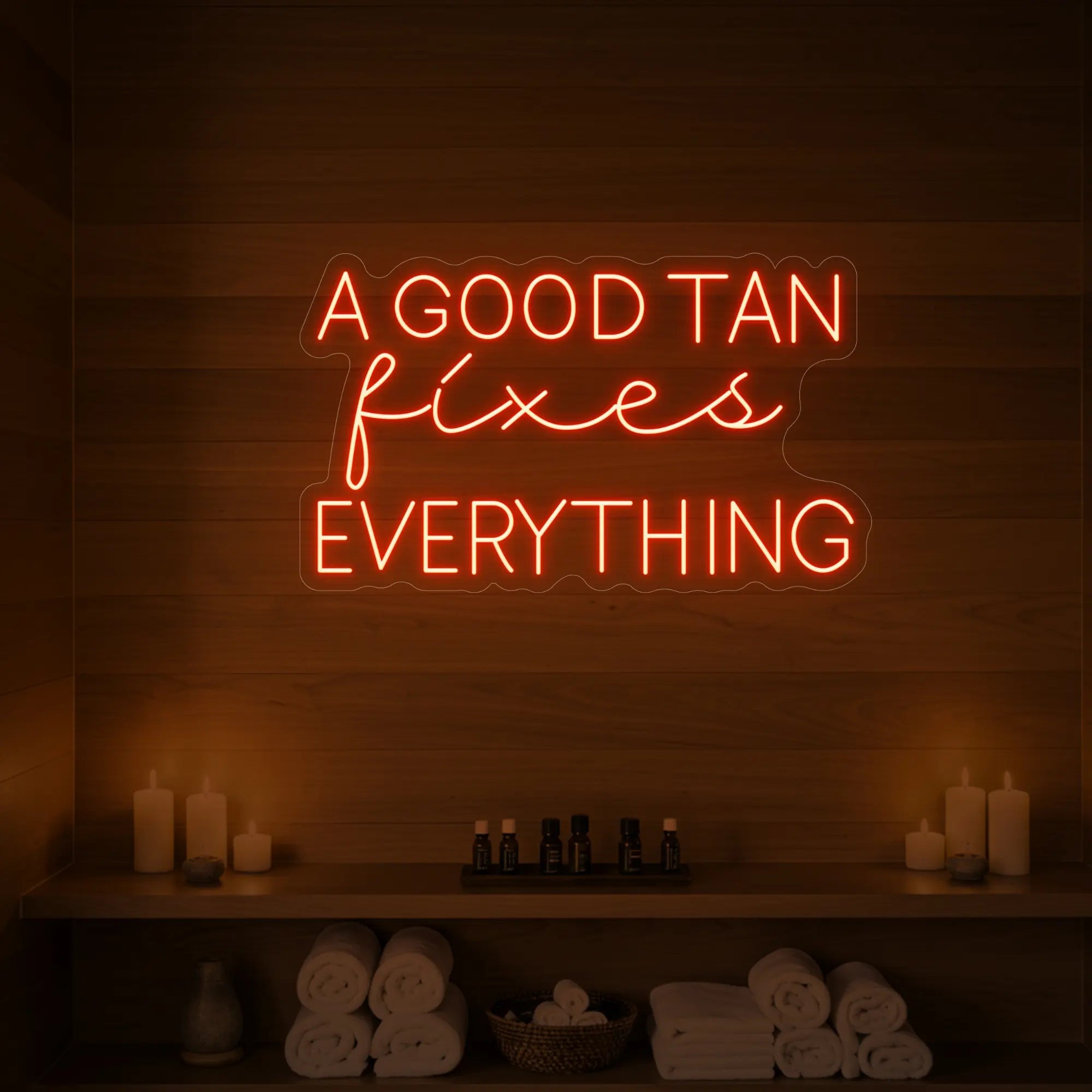 Photo of the 'A GOOD TAN fixes EVERYTHING' neon sign glowing in golden yellow against a styled interior wall.