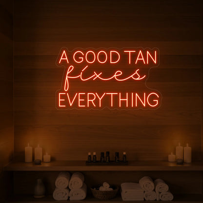 Photo of the 'A GOOD TAN fixes EVERYTHING' neon sign glowing in golden yellow against a styled interior wall.