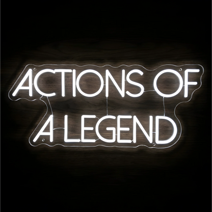 “ACTIONS OF A LEGEND” LED Neon Sign glowing in bright white uppercase letters across two lines on clear acrylic against a dark wood background, suited to home offices and creative workspaces.