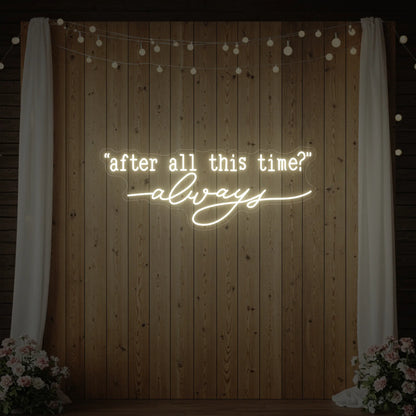 Photo of the 'After All This Time V2' neon sign glowing in warm white against a styled interior wall.