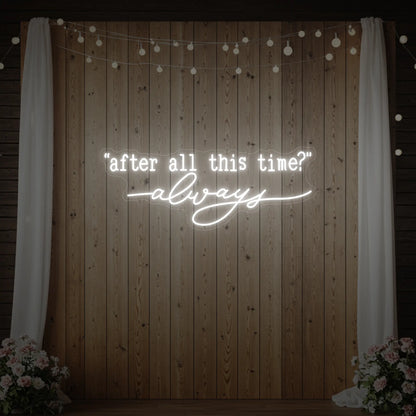 Photo of the 'After All This Time V2' neon sign glowing in cool white against a styled interior wall.
