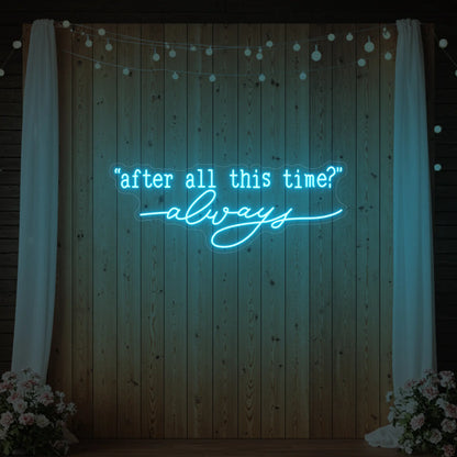 Photo of the 'After All This Time V2' neon sign glowing in ice blue against a styled interior wall.