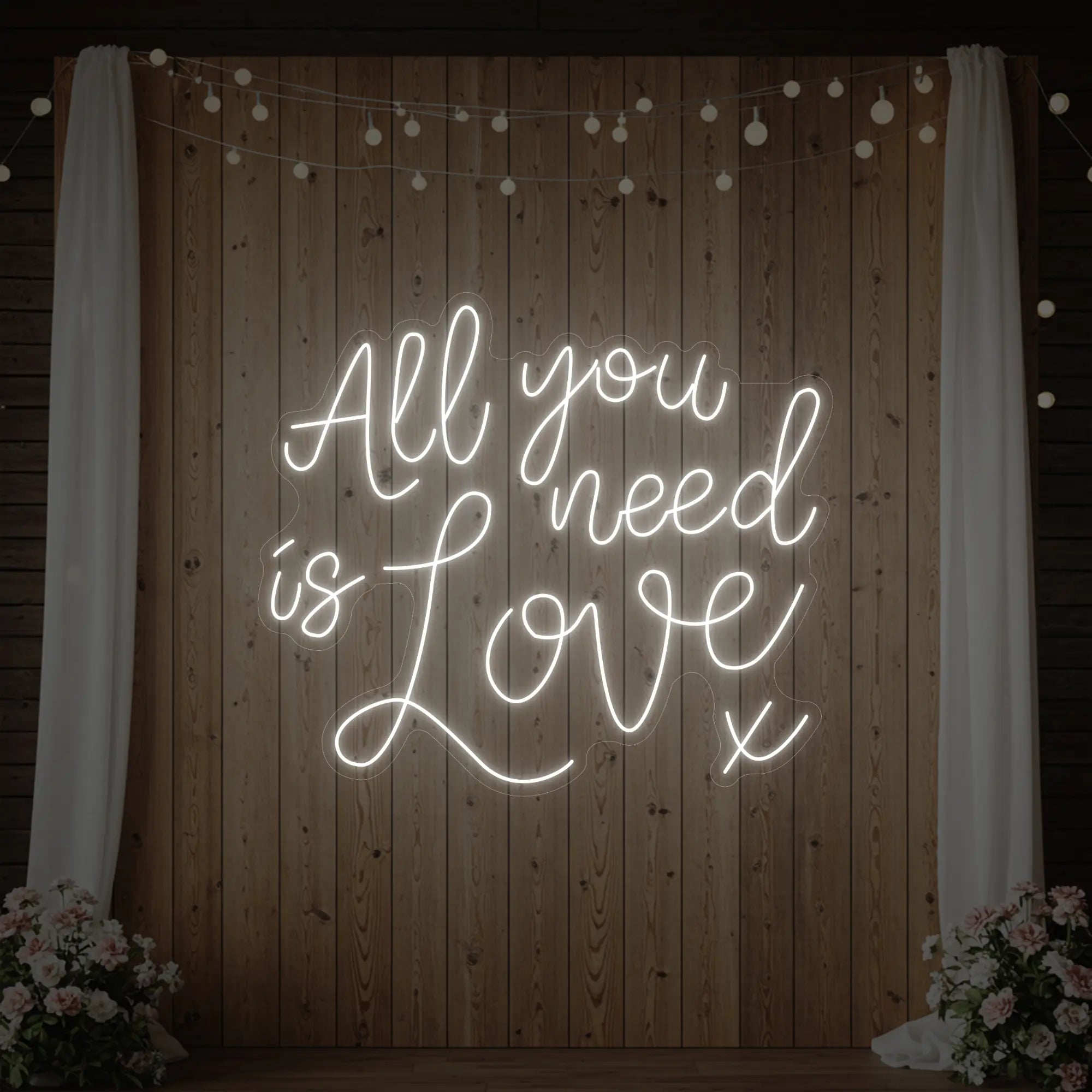 Photo of the 'All You Need Is Love V1' neon sign glowing in cool white against a styled interior wall.