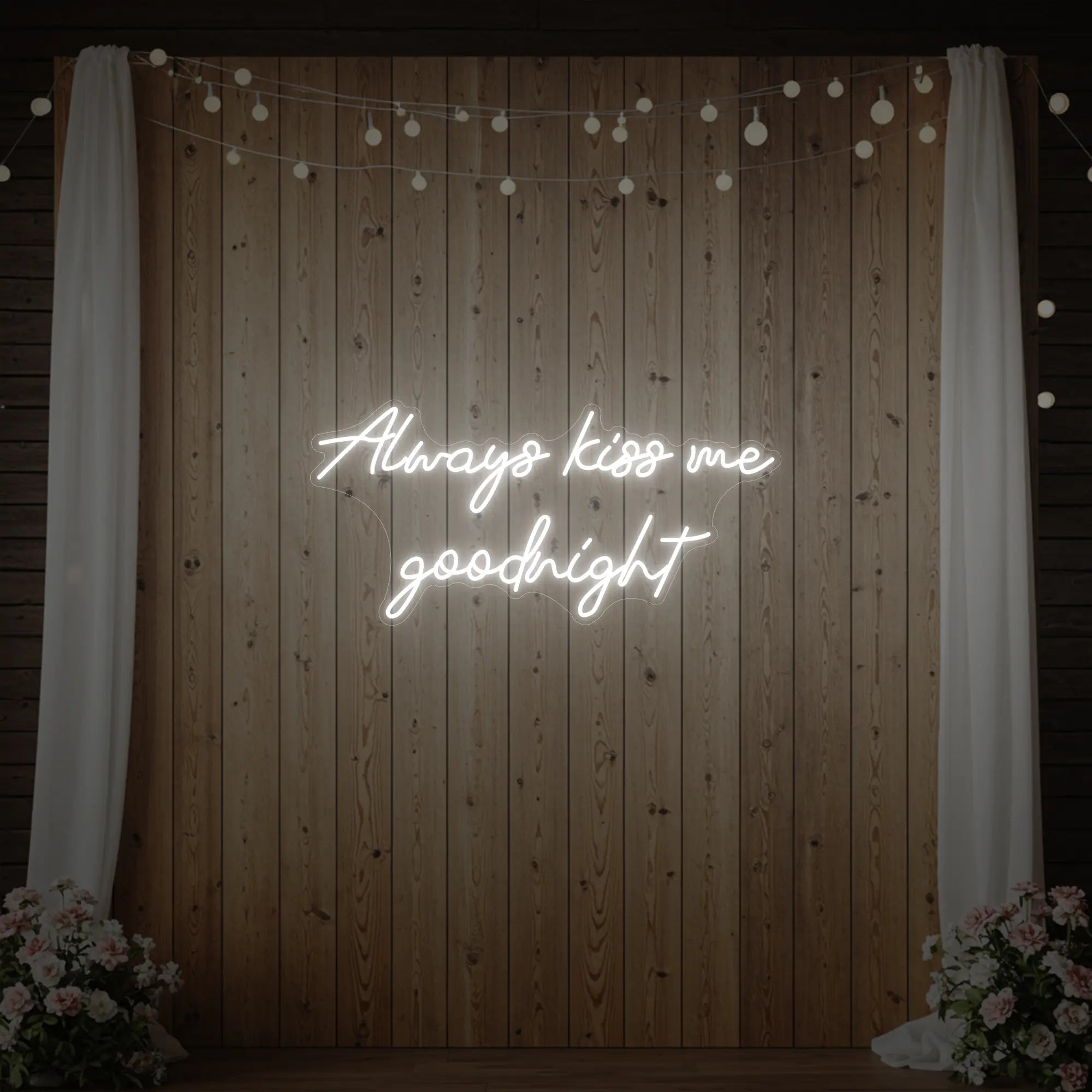 Photo of the 'Always Kiss Me Goodnight' neon sign glowing in cool white against a styled interior wall.