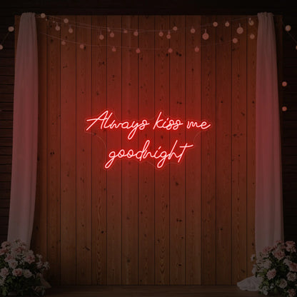 Photo of the 'Always Kiss Me Goodnight' neon sign glowing in red against a styled interior wall.