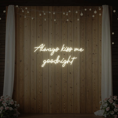 Photo of the 'Always Kiss Me Goodnight' neon sign glowing in warm white against a styled interior wall.