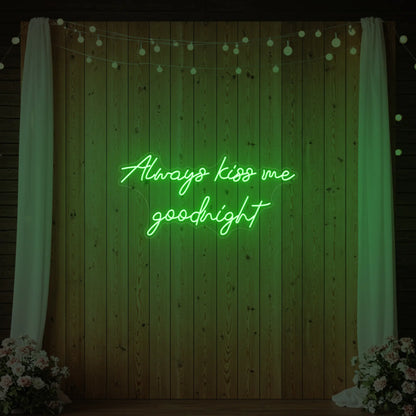 Photo of the 'Always Kiss Me Goodnight' neon sign glowing in green against a styled interior wall.