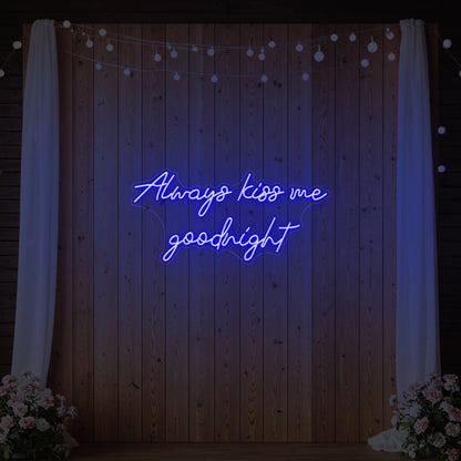 Photo of the 'Always Kiss Me Goodnight' neon sign glowing in deep blue against a styled interior wall.