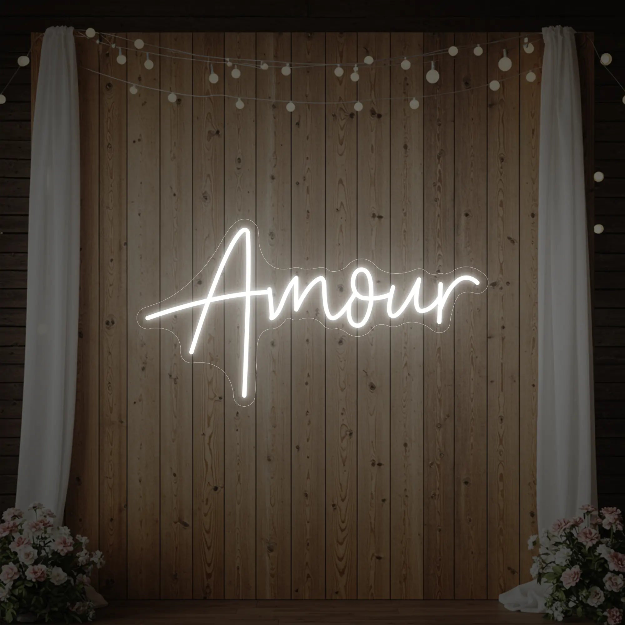 Photo of the 'Amour' neon sign glowing in cool white against a styled interior wall.