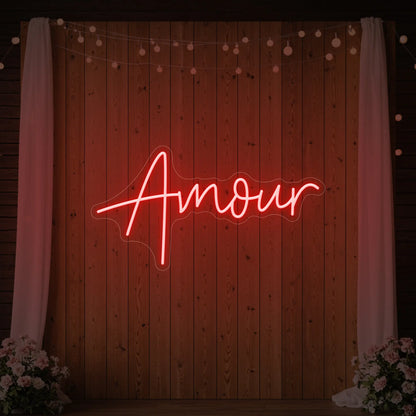 Photo of the 'Amour' neon sign glowing in red against a styled interior wall.