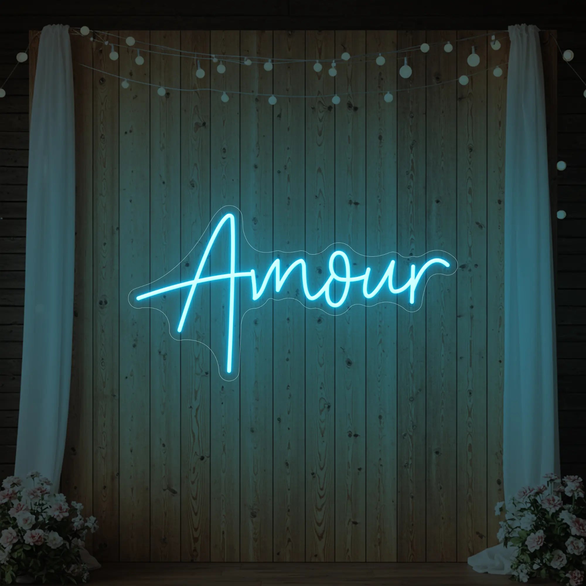 Photo of the 'Amour' neon sign glowing in ice blue against a styled interior wall.