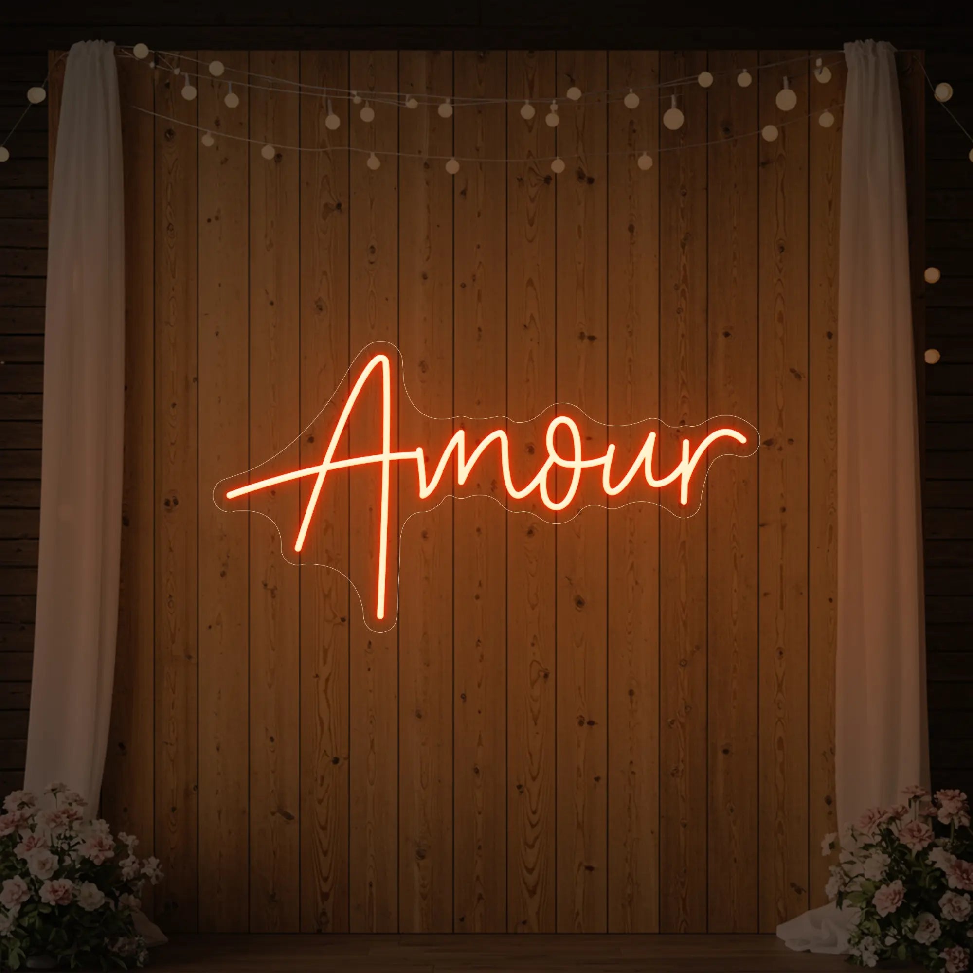Photo of the 'Amour' neon sign glowing in golden yellow against a styled interior wall.