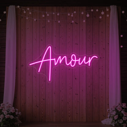 Photo of the 'Amour' neon sign glowing in light pink against a styled interior wall.