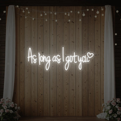 Photo of the 'As Long As I Got You' neon sign glowing in cool white against a styled interior wall.