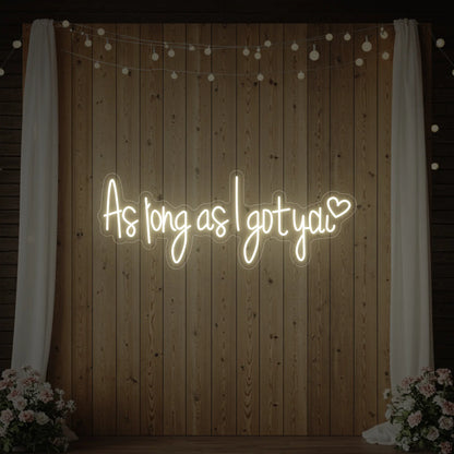 Photo of the 'As Long As I Got You' neon sign glowing in warm white against a styled interior wall.