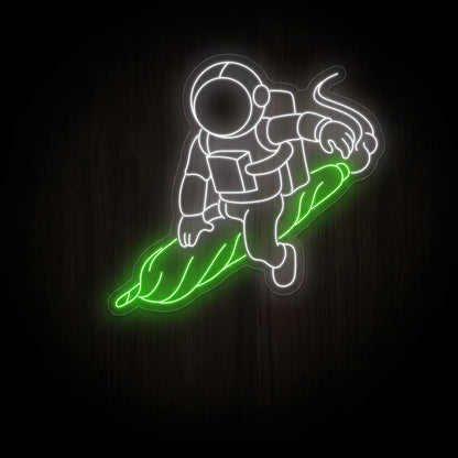 White astronaut LED neon sign riding a glowing green rolled joint with white smoke on clear acrylic backing for recreational wall décor.